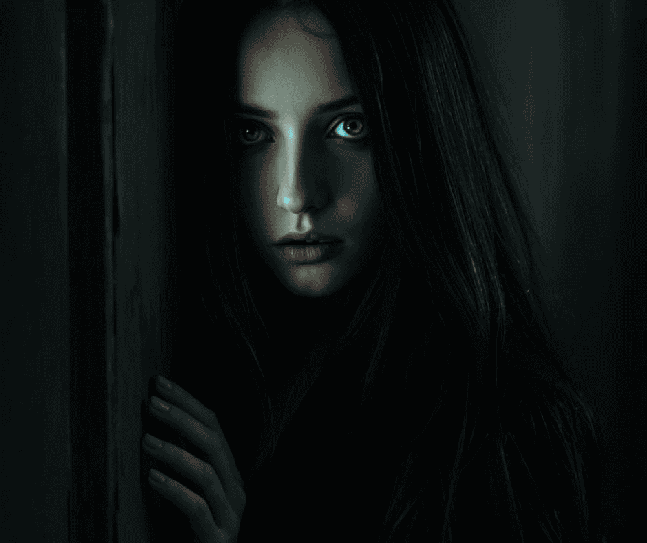 A woman peering through a darkened doorway with a wary expression.